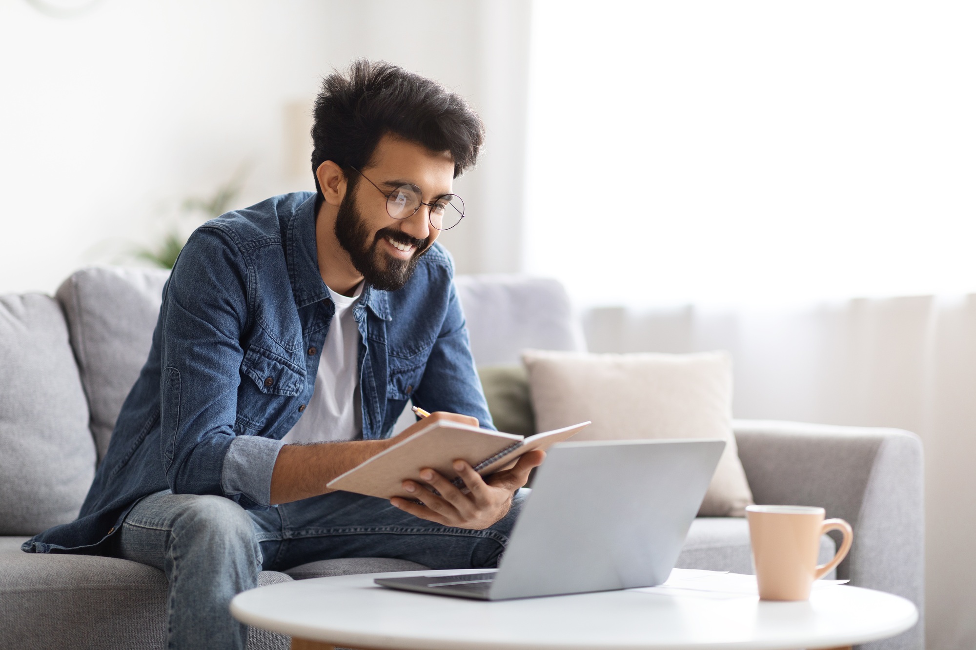 Distance Learning. Indian Man Study With Laptop At Home And Taking Notes